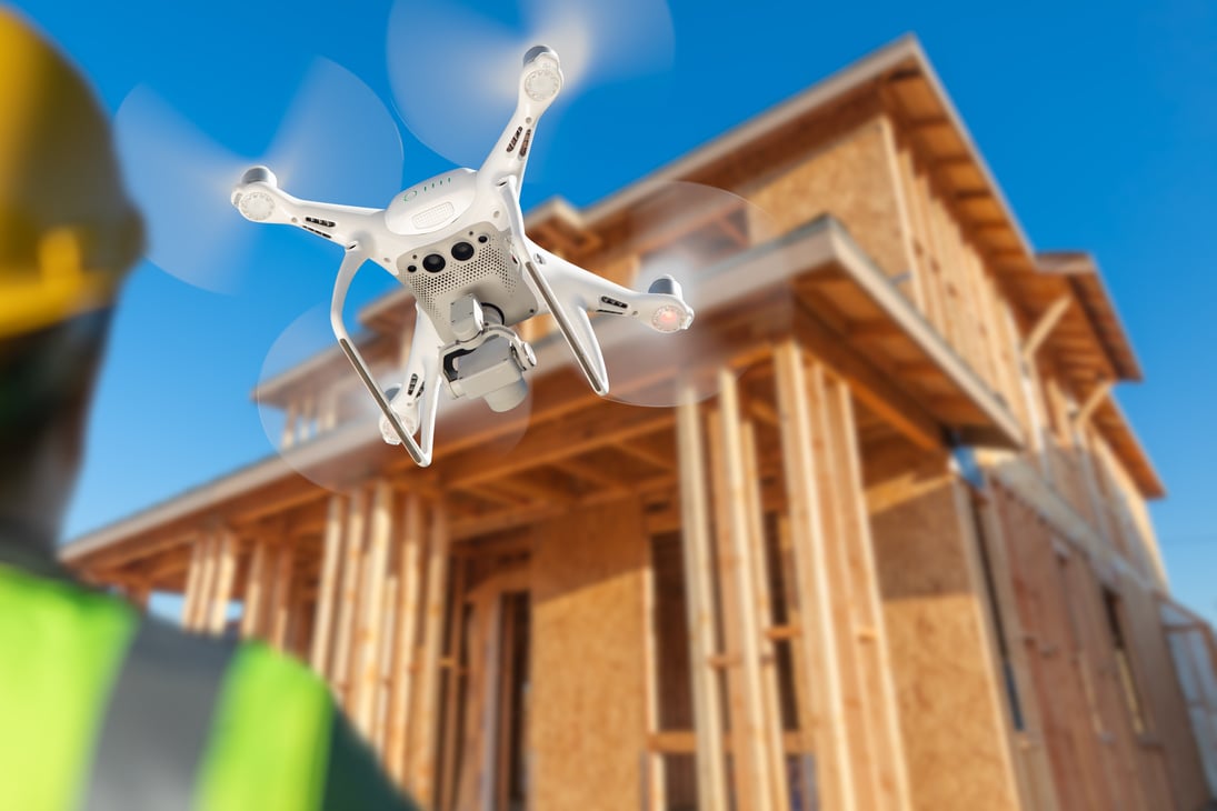 Man Flies Drone Inspecting Home Construction Site